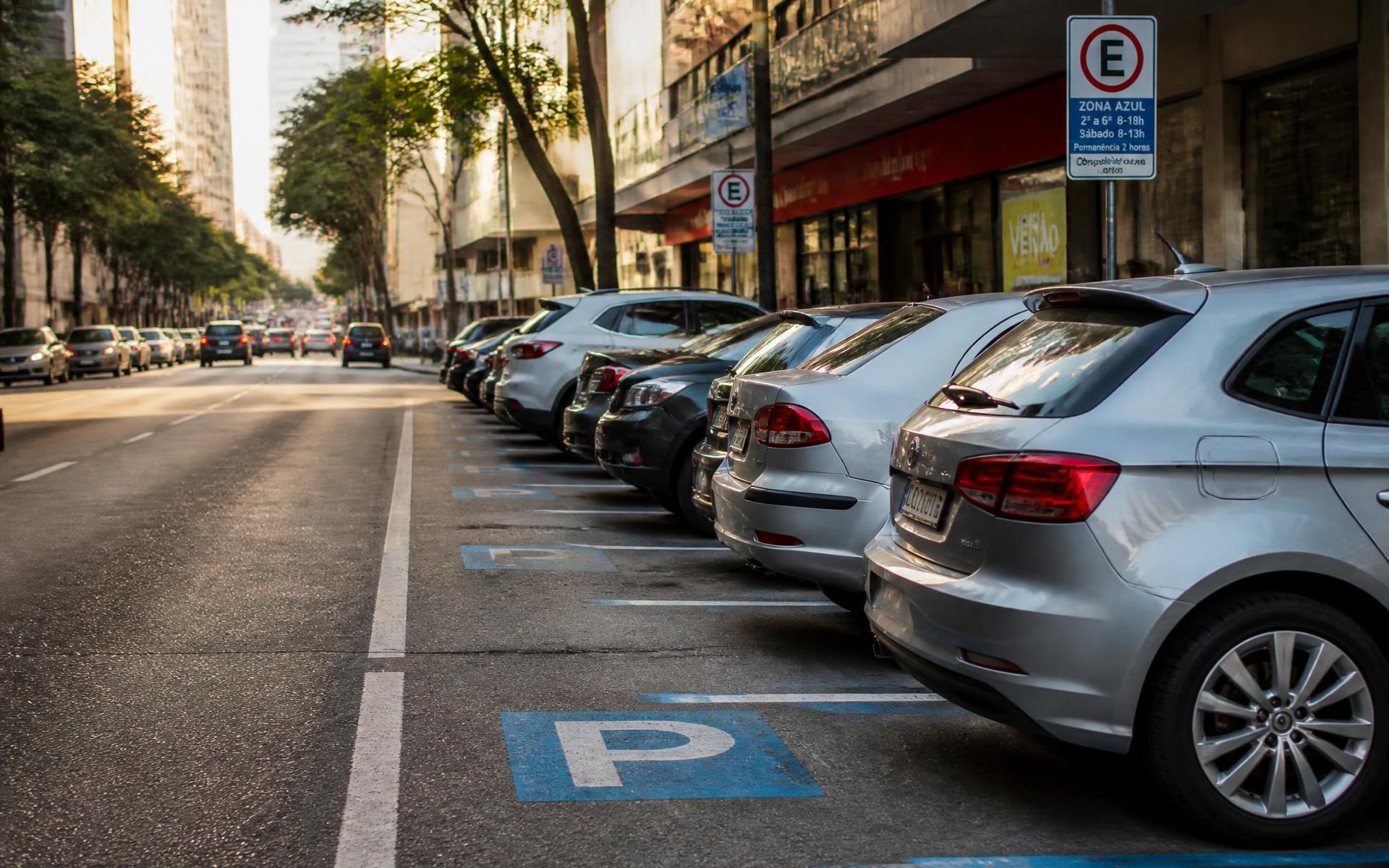 Rua com vagas de zona azul demarcadas e veículos estacionados